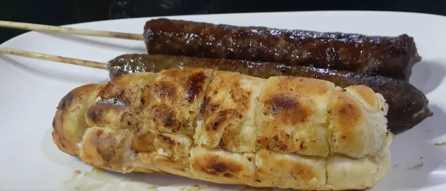 Dois espetinhos de kafta e um pão de alho na brasa